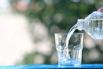 Poster - glass of water on wood table background and pouring drinking water