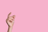 Fototapeta Tęcza - Female beautiful caucasian hand snaps fingers. pink background.