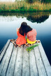 Two young girls sit on a wooden bridge by the river