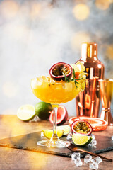 Passion fruit Alcoholic cocktail with gin, juice, rosemary and ice. Gray background, copper bar tools, copy space