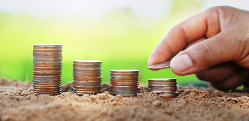 Poster - saving money hand putting coins on stack on soil with sunshine. concept finance and accounting
