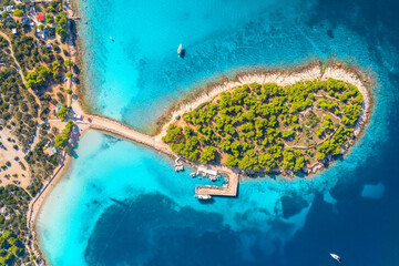 Aerial view of beutiful small island in sea bay at sunny day in summer in Murter, Croatia. Top view of clear blue water, green trees, mountain, sandy beach, boats and yachts. Tropical landscape