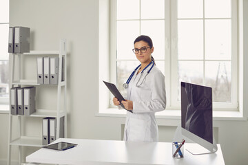 Wall Mural - Woman doctor pediatrician standing in the white office of the hospital.