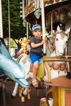 Little Boy Rides A Traditional Carousel White Horse