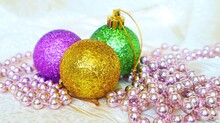 Christmas Shiny Golden Green And Purple Balls With Garland On A Light Background