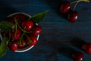 Fresh cherry on plate on wooden blue background.