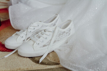 Bride's white sneakers are next her wedding dress. Charges of the bride.