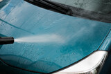 Fototapeta Miasta - Car wash at home alone. Car wash high pressure close-up. A man washes a green car.