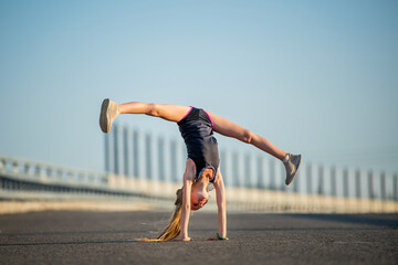 Girls exercise in the summer on the street, stand on their hands, legs in twine