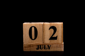 wooden calendar 2 July word on black background with copy space , selective focus at the calendar