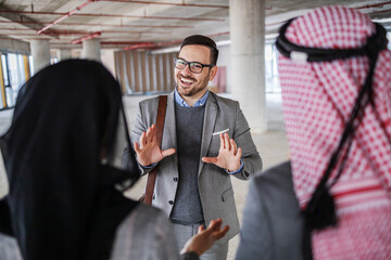 Two muslim investors walking around building in construction process and talking with real estate agent about investment.