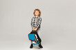 Back to school. A funny little boy from elementary school posing with a backpack over white background, isolated