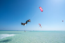 Kiter Does A Difficult Trick On A Background Of Transparent Water And Blue Sky