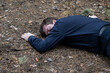 © Petr - Murder in the woods. The body of a man in a blue shirt and trousers lies on the ground among the trees in the forest. Victim of an attack.