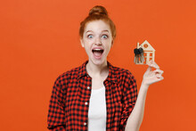 Shocked Young Readhead Girl In Casual Red Checkered Shirt Posing Isolated On Orange Wall Background Studio Portrait. People Emotions Lifestyle Concept. Mock Up Copy Space. Hold House Bunch Of Keys.