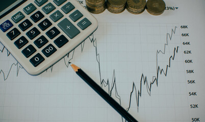 stack of coins, calculator and pencil on a graph chart background 