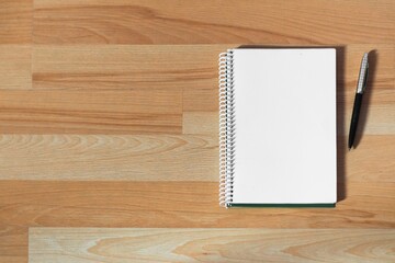 Wall Mural - High angle shot of a notebook with a pen on a wooden surface