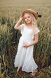 © Олег Кошевський - little girl with a straw hat. beautiful little girl with blond hair in a white dress in the background of a beautiful field. Girl with a bouquet of red poppies