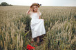 © Олег Кошевський - little girl with a straw hat. beautiful little girl with blond hair in a white dress in the background of a beautiful field. Girl with a bouquet of red poppies