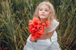 © Олег Кошевський - beautiful little girl with blond hair in a white dress in the background of a beautiful field. Girl with a bouquet of red poppies