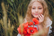 © Олег Кошевський - beautiful little girl with blond hair in a white dress in the background of a beautiful field. Girl with a bouquet of red poppies