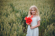 © Олег Кошевський - beautiful little girl with blond hair in a white dress in the background of a beautiful field. Girl with a bouquet of red poppies