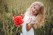 © Олег Кошевський - beautiful little girl with blond hair in a white dress in the background of a beautiful field. Girl with a bouquet of red poppies