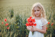 © Олег Кошевський - beautiful little girl with blond hair in a white dress in the background of a beautiful field. Girl with a bouquet of red poppies