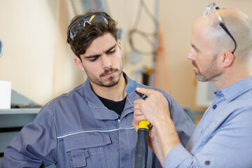 workmen checking pipe in workshop