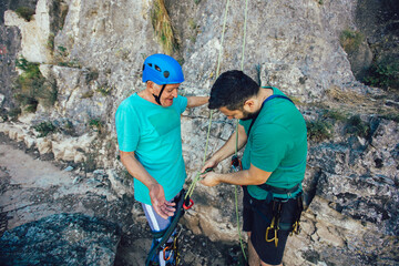 Senior man with a rope preparing for climbing on the rock.