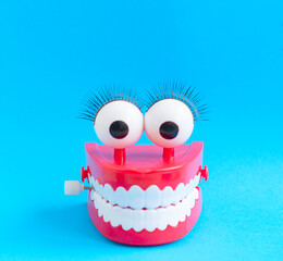 toy with smiling teeth and eyes on blue background as a concept of dentistry and healthy oral cavity and smile