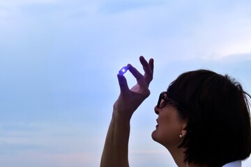 woman closely looks at an unusual stone on a sunset background