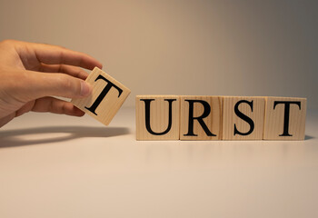 The word trust from wooden cubes. Spot light and white background. Close up.