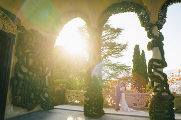 Wall Mural - Villa Balbianello wedding photoshoot beautiful couple bride and groom long veil and white dress on mountains background lake Como Italy ceremony luxury beautiful sunny day