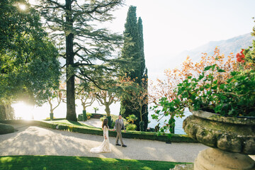 Villa Balbianello wedding photoshoot beautiful couple bride and groom long veil and white dress on mountains background lake Como Italy ceremony luxury beautiful sunny day