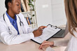 © insta_photos - Professional medic female african american doctor showing insurance claim form consult caucasian woman explain information to patient at appointment medical visit in clinic. Medicine women healthcare