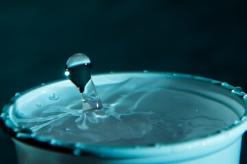 Wall Mural - Closeup shot of a water drop splash in a glass blue-colored