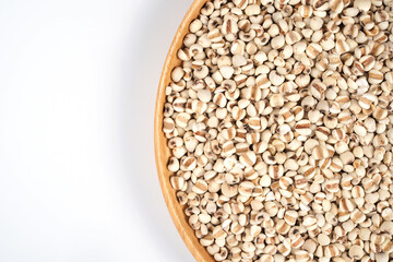 Organic millet grains on brown wood dish on white background. top view