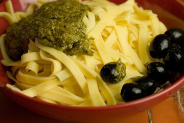 Poster - Closeup shot of fresh pasta with olives on red pot