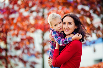 a happy young mother is holding a sweet baby boy, the family is having fun together outside on a nic