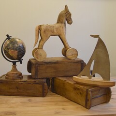 Rustic wooden globe next to Indian brick molds and a wooden horse on wheels and a sailing boat