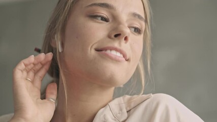 Sticker - Pleased attractive blonde woman in earphones listening music and dancing at home