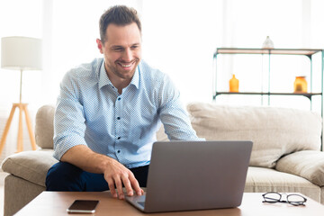 Young man sitting on couch and using pc