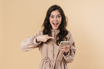 Wall Mural - Image of cheerful woman smiling and pointing finger at mobile phone