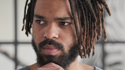 Canvas Print - A close-up view of a serious young african american man is thinking about something while looking to the camera at home