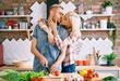 © GVS - Young couple kissing and cooking together vegetarian meal in the kitchen at home