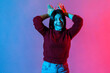 Happiness, carefree mood. Neon light portrait of joyful beautiful woman behaving childish humorous with bunny ears gesture on head, entertaining and fooling around. indoor studio shot isolated