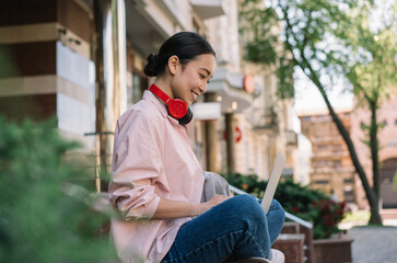 Asian freelancer using laptop, typing on keyboard, blogging. Portrait of beautiful woman copywriter working outdoors. Smiling Korean student studying, learning language, online education concept