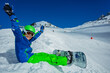 © Sergey Novikov - Close image of a little boy with snowboard sit on the snow view from side in mask, ski helmet lifting hands up