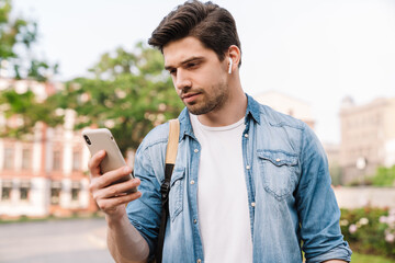 Poster - Photo of focused man with earphone using cellphone while walking